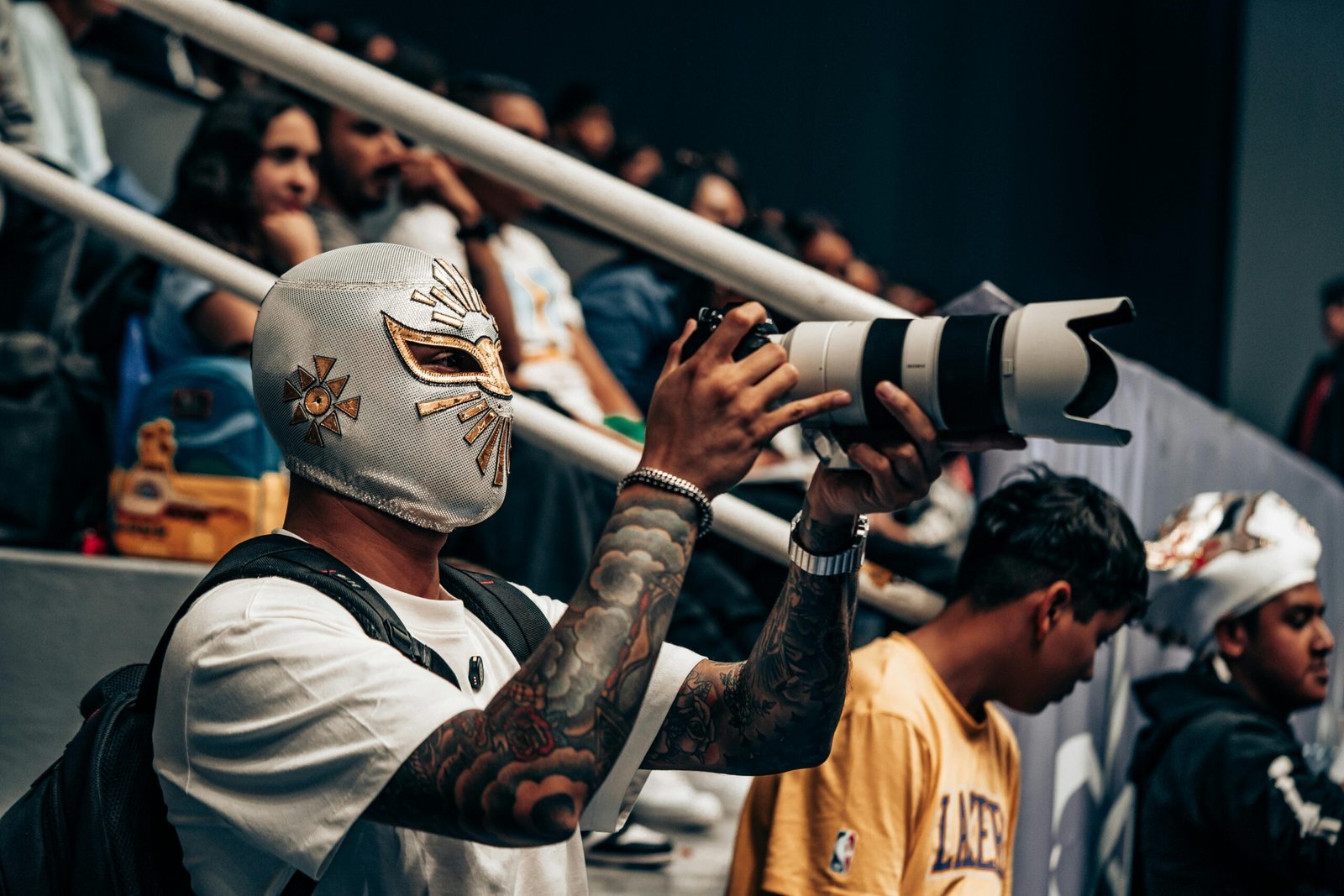A masked photographer using a telephoto lens at a crowded event in Queretaro.